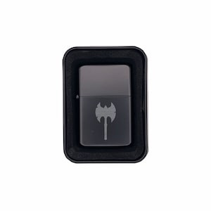 May include: A black lighter with a silver axe design in a black box.