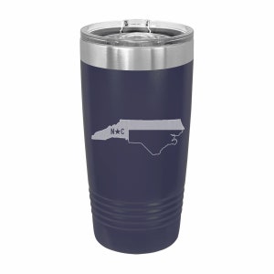 Pu&ograve; includere: Un bicchiere in acciaio inossidabile blu navy con un contorno bianco dello stato della Carolina del Nord e il testo "N*C" sul lato.