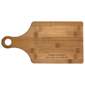 May include: A brown wooden cutting board with a handle. The board has a periodic table of elements engraved on it and the text "I enjoy cooking... but only periodically".