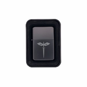 May include: A dark gray metal lighter with a decorative emblem of a sword and wings. The lighter is in a black case with a foam insert. The lighter is a rectangular shape.