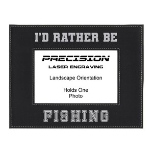 May include: Black leather picture frame with a stitched border. The frame has a white inscription that reads "I'd Rather Be Fishing".