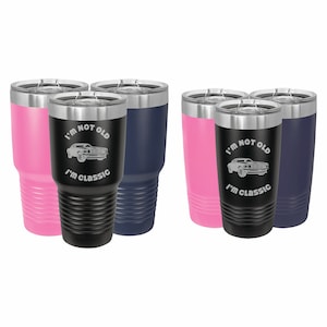 May include: Set of four stainless steel tumblers with a black, pink, and blue color scheme. Each tumbler features a silver lid and a laser-etched design of a classic car with the text "I'm not old, I'm classic".