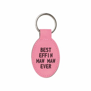 May include: Pink oval leather keychain with a silver key ring. The keychain has the text "BEST EFFIN MAW MAW EVER" printed in black.