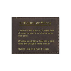May include: A brown leather wallet with gold text that reads " +2 Holder of Money". The text below describes the wallet as a useful item for storing payments and warns to keep it out of reach of rogues.