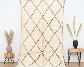 May include: A white Moroccan rug with a diamond pattern in gray. The rug has a soft, fluffy texture and is perfect for adding a touch of bohemian style to any room.