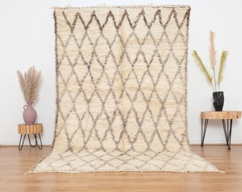 May include: A white and brown Moroccan rug with a diamond pattern. The rug is hand-woven and has a soft, fluffy texture.