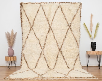 May include: A white and brown Moroccan rug with a diamond pattern. The rug has a fluffy texture and a fringe border.