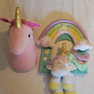 Könnte beinhalten: Rosa Einhornkopf mit goldenem Horn und rosa Ohren. Ein Regenbogen mit Wolken und Sternen befindet sich neben einem Einhorn mit goldenem Horn, weißem Körper und gelben Hufen. Das Einhorn hat eine Regenbogenmähne und einen Regenbogen-Schweif.