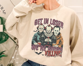 May include: A beige sweatshirt with a graphic print of three horror movie characters. The text on the shirt reads "Get in Loser, We're Going Killing".