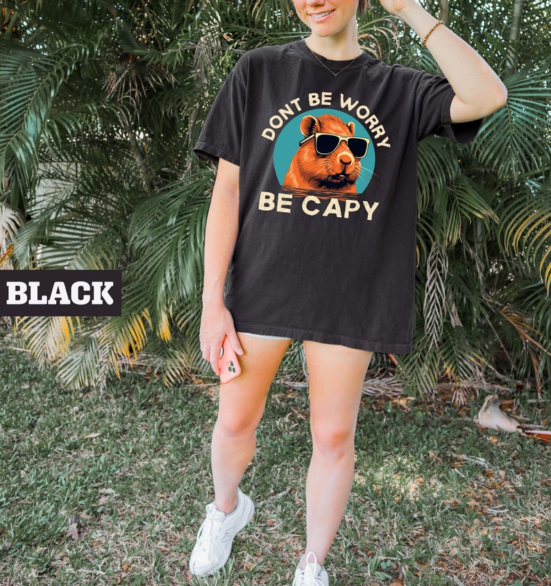 May include: Black t-shirt with a graphic of a capybara wearing sunglasses and the text "Don't be worry be capy".