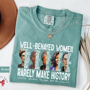 May include: Light green t-shirt with a white graphic print that says "Well-Behaved Women Rarely Make History". The graphic features portraits of Frida Kahlo, Rosa Parks, Maya Angelou, Michelle Obama, and Ruth Bader Ginsburg.