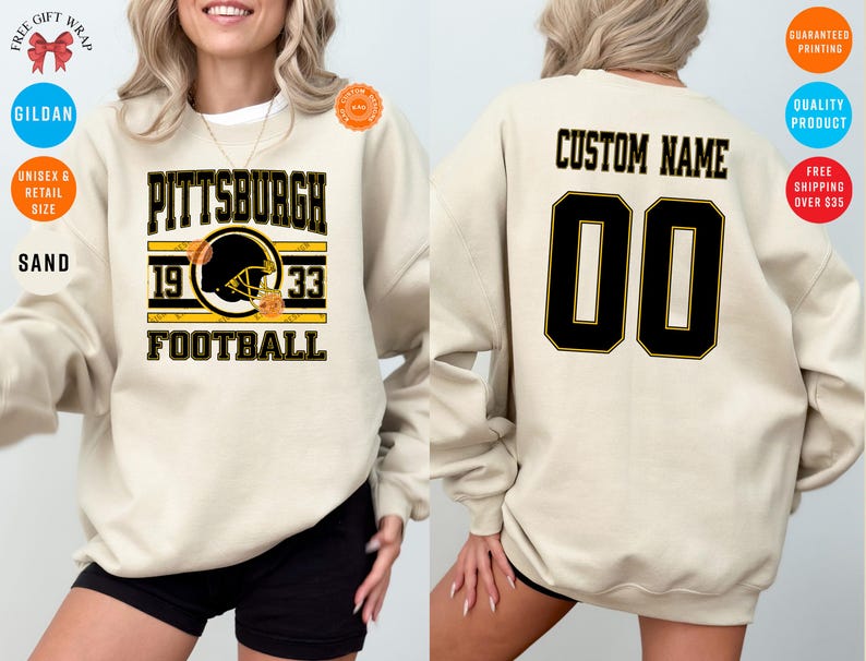 May include: Sand-colored sweatshirt with "PITTSBURGH 1933 FOOTBALL" text and a football helmet graphic. The back features "CUSTOM NAME" and the number "00" in black with gold trim. Gildan brand.
