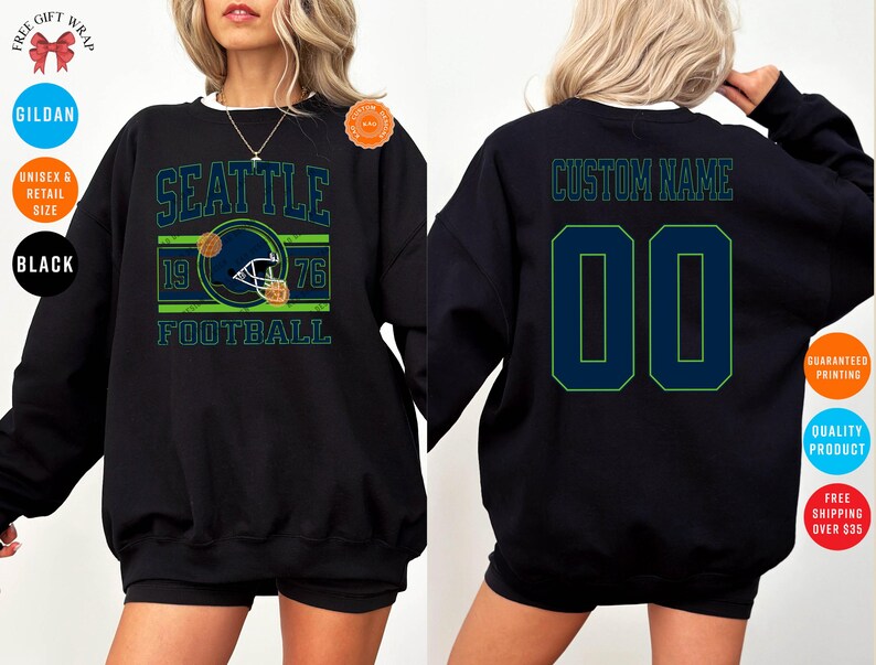 May include: Black sweatshirt featuring a Seattle football design with a helmet graphic, the year 1976, and the word "FOOTBALL". The back of the sweatshirt has the text "CUSTOM NAME" above the number "00".