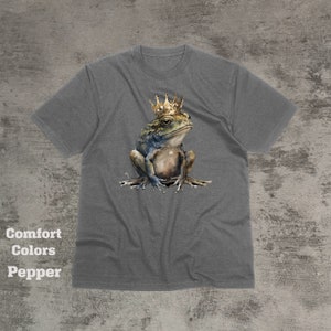 May include: A gray t-shirt with a graphic of a frog wearing a gold crown. The frog is sitting on its hind legs with its front legs crossed. The frog is green, brown, and blue.