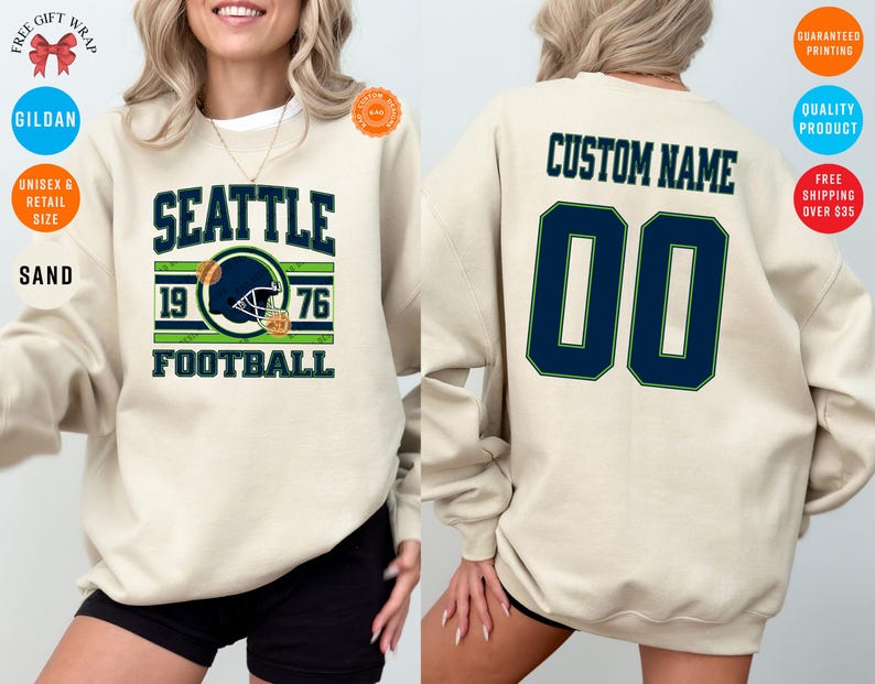 May include: Sand-colored sweatshirt with "SEATTLE FOOTBALL" in navy and green, featuring a football helmet graphic and the year 1976. The back displays "CUSTOM NAME" above the number "00" in navy with a green outline.