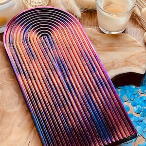 Könnte beinhalten: Ein regenbogenfarbener, schimmernder Tablett mit einer abgerundeten Bogenform. Das Tablett ist aus Metall und hat eine strukturierte Oberfläche.