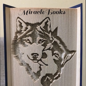 Könnte beinhalten: Eine Buchkunstskulptur aus zwei sich gegenüberstehenden Wölfen, die durch das Falten der Seiten eines Buches entstanden ist. Die Skulptur trägt den Titel "Miracle Books".