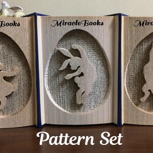 Pode incluir: Três esculturas de livros de madeira com recortes de coelhos. Cada livro tem um recorte oval com uma silhueta de coelho. O texto "Miracle Books" está acima de cada recorte. As palavras "Pattern Set" estão na parte inferior.