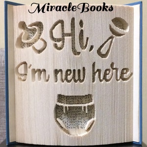 Könnte beinhalten: Ein weißes Buch mit den Worten "Miracle Books" oben und "Hi, I'm new here" ausgeschnitten aus den Seiten. Ein Babyrassel und eine Windel sind ebenfalls aus den Seiten ausgeschnitten.
