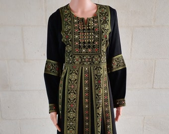 Puede incluir: Un vestido largo negro con bordados verdes y rojos. El vestido tiene cuello en V y mangas largas.