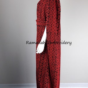 May include: A red and black embroidered dress with a long, flowing silhouette. The dress has a V-neckline and a belt at the waist. The embroidery is intricate and detailed, and the dress is perfect for a special occasion.