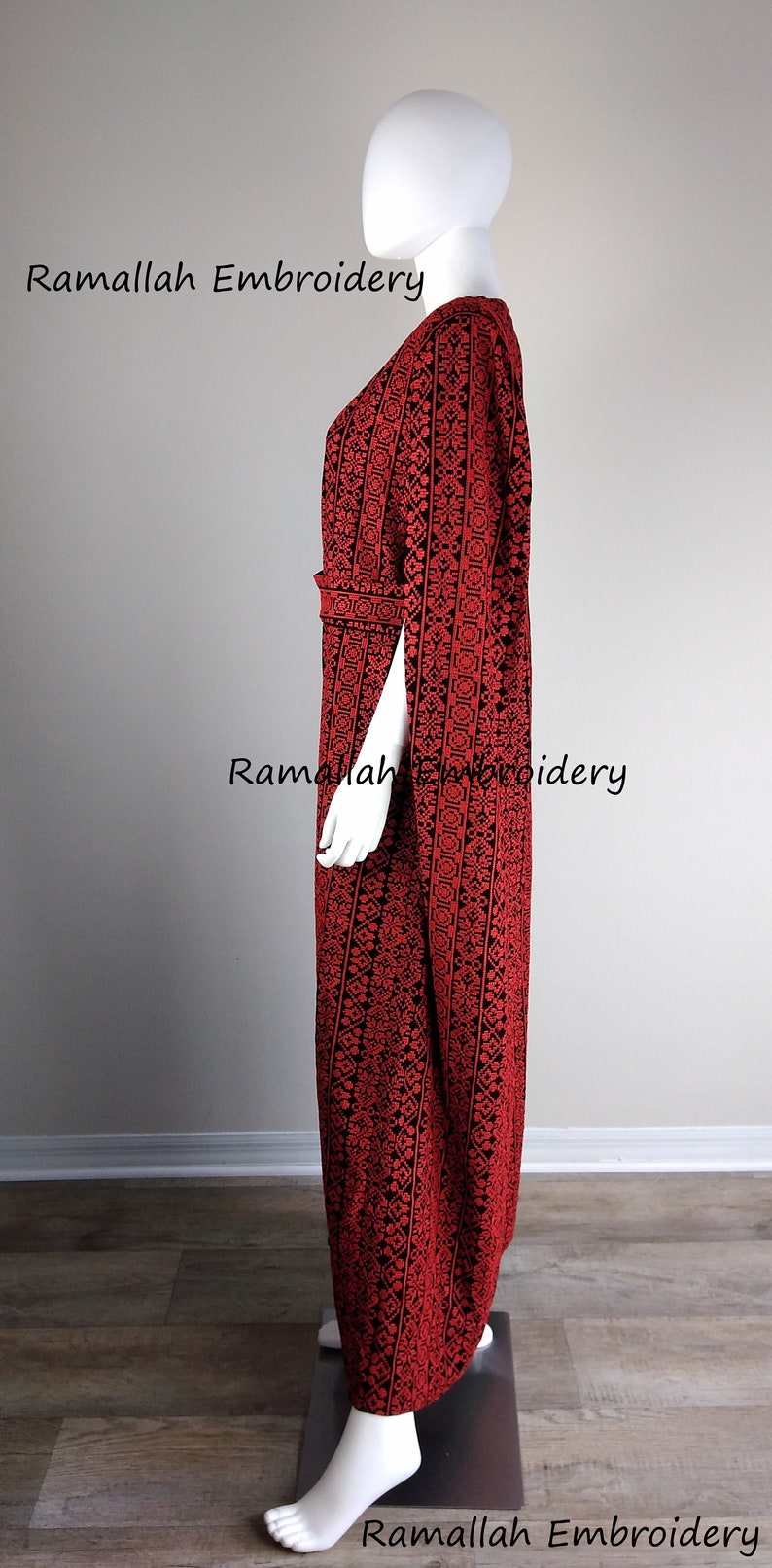 May include: A red and black embroidered dress with a long, flowing silhouette. The dress has a V-neckline and a belt at the waist. The embroidery is intricate and detailed, and the dress is perfect for a special occasion.