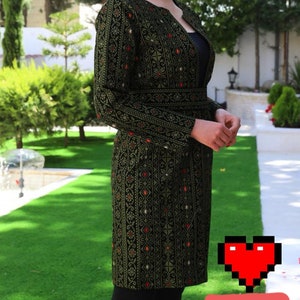 May include: A long, dark green embroidered jacket with a black belt. The jacket has a traditional pattern with gold and red accents.