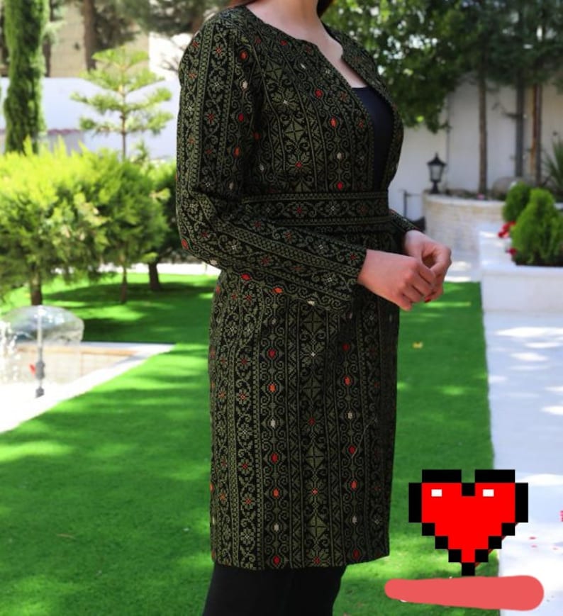 May include: A long, dark green embroidered jacket with a black belt. The jacket has a traditional pattern with gold and red accents.