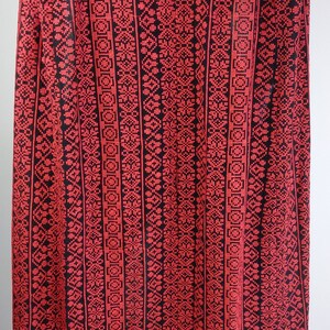 May include: Red and black fabric with a geometric pattern. The fabric has a woven texture and is made of a soft material.