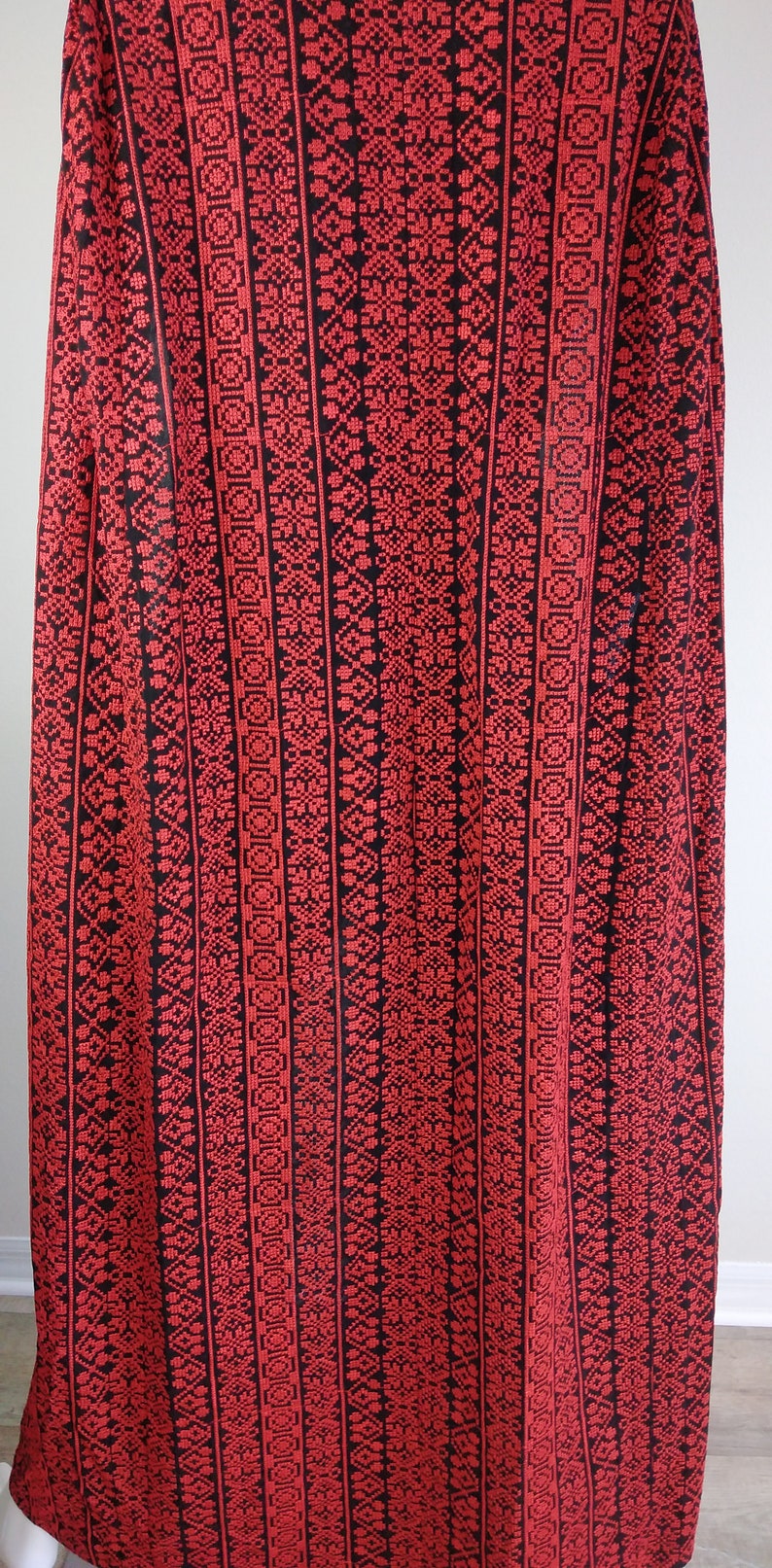 May include: Red and black fabric with a geometric pattern. The fabric has a woven texture and is made of a soft material.