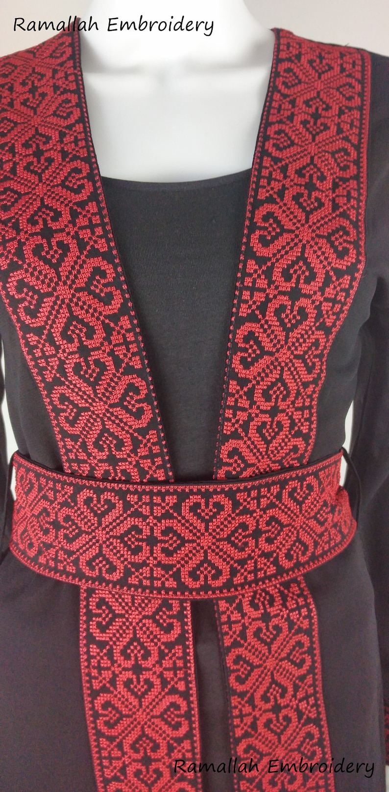 Puede incluir: Vestido negro con ribetes bordados en rojo alrededor del escote, las mangas y la cintura. El bordado presenta un patr&oacute;n geom&eacute;trico. El texto "Ramallah Embroidery" aparece dos veces en el vestido.