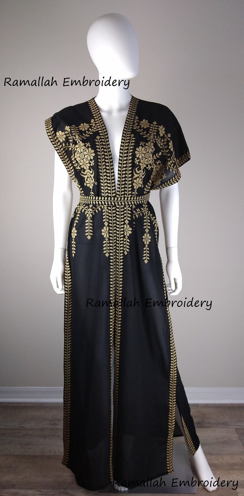 May include: Black embroidered jumpsuit with gold floral and leaf patterns. The open-front garment features a V-neck, short sleeves, and a belted waist. The text "Ramallah Embroidery" is visible.