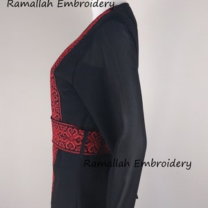 Puede incluir: Abaya negra con bordados rojos alrededor del cuello, la cintura y los pu&ntilde;os. El bordado presenta intrincados patrones florales. El texto "Ramallah Embroidery" aparece tres veces en la imagen.