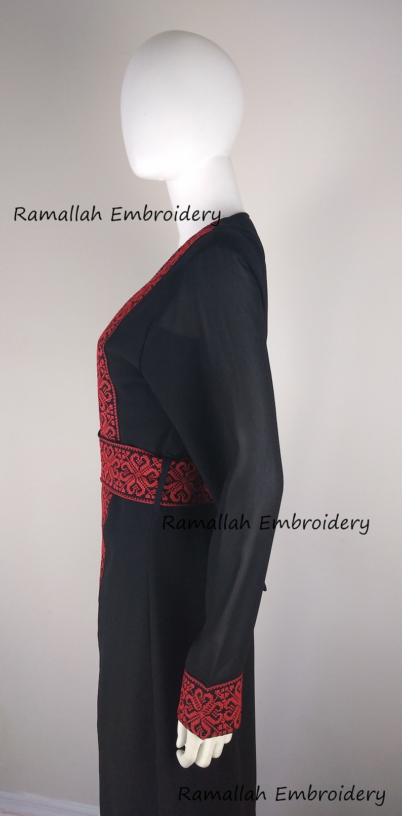 Puede incluir: Abaya negra con bordados rojos alrededor del cuello, la cintura y los pu&ntilde;os. El bordado presenta intrincados patrones florales. El texto "Ramallah Embroidery" aparece tres veces en la imagen.
