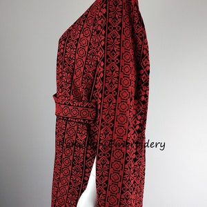 May include: A red and black embroidered dress with a V-neck and a belt. The dress has a geometric pattern and the text "Ramallah Embroidery" is visible on the image.