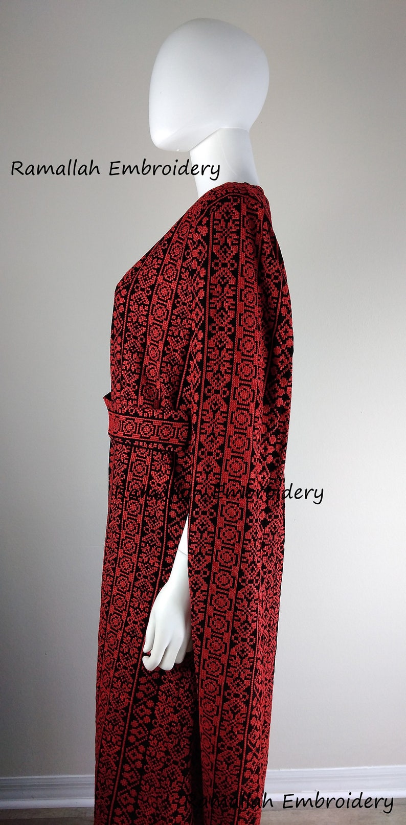 May include: A red and black embroidered dress with a V-neck and a belt. The dress has a geometric pattern and the text "Ramallah Embroidery" is visible on the image.