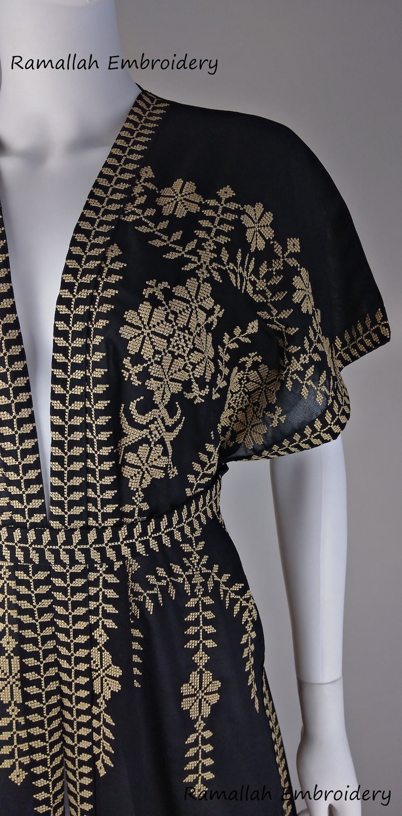 May include: Black garment with intricate gold embroidery, featuring floral and geometric patterns. The text "Ramallah Embroidery" is visible. The design includes a detailed border and floral motifs, showcasing traditional craftsmanship.
