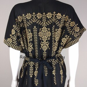 May include: Black kaftan dress with gold embroidery. The dress features a floral and leaf pattern across the shoulders and down the front. A matching tie belt cinches the waist. The text "Ramallah Embroidery" is visible.
