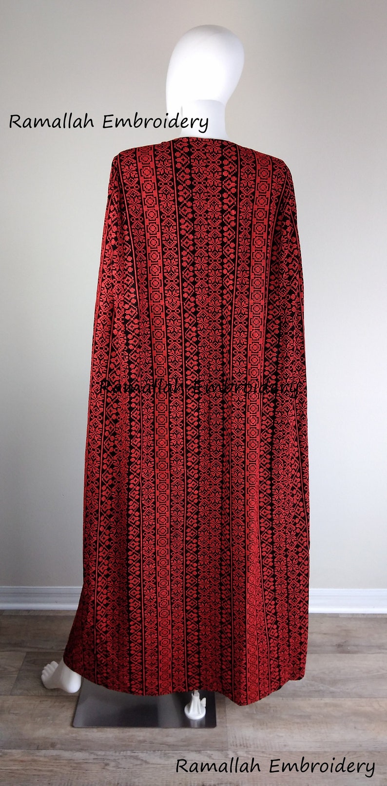 May include: A red and black embroidered cape with a geometric pattern. The cape is on a white mannequin. The text "Ramallah Embroidery" is visible at the top and bottom of the image.