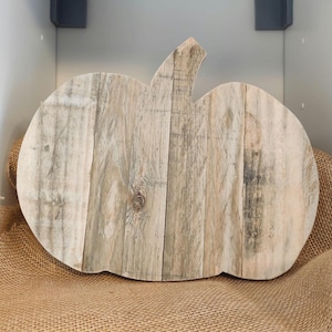 Puede incluir: Una decoraci&oacute;n de calabaza r&uacute;stica de madera. La calabaza est&aacute; hecha de tablas de madera de color claro, ensambladas para formar la forma de la calabaza. Tiene un tallo y est&aacute; sobre una superficie de arpillera. La madera tiene variaciones naturales de color.