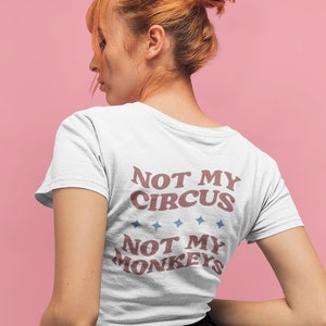Könnte beinhalten: Weißes T-Shirt mit einer roten und blauen Grafik, auf der "Not My Circus, Not My Monkeys" steht.