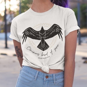 May include: White t-shirt featuring a black silhouette of a bird with the text "Ominous bird of yore" and "Edgar Allan Poe" underneath.