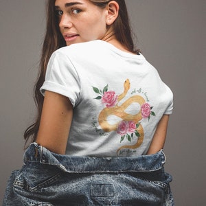 May include: White t-shirt featuring a gold snake and pink roses design. The text on the shirt reads "and all I knew is I loved you, despite all the things you did to me".