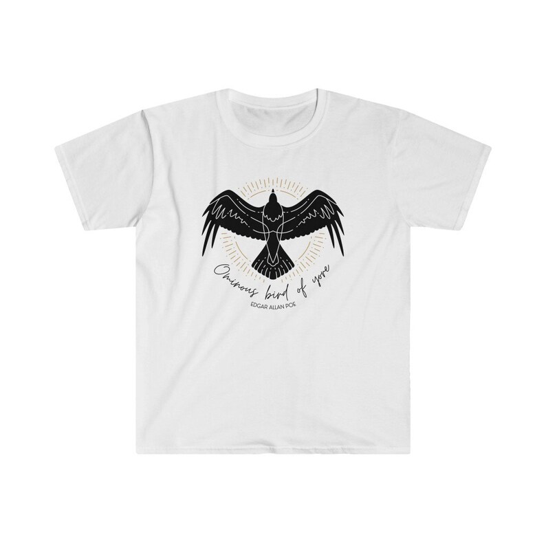 Puede incluir: Camiseta blanca con una silueta negra de un cuervo con el texto "Once upon a midnight dreary" y "Edgar Allan Poe" impreso en la parte delantera.