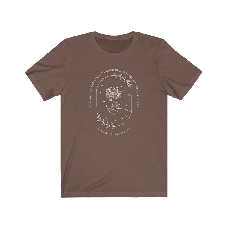 May include: A brown t-shirt with a white graphic design featuring a hand holding a flower with the text "It is not in the stars to hold our destiny but in ourselves" and "William Shakespeare".