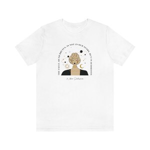 Może przedstawiać: Biały T-shirt z czarną i złotą ilustracją kobiety z gwiazdami i planetami wok&oacute;ł głowy. Tekst "The fault, dear Brutus, is not in our stars, but in ourselves" jest napisany w k&oacute;łku wok&oacute;ł kobiety. Tekst "William Shakespeare" jest napisany pod ilustracją.