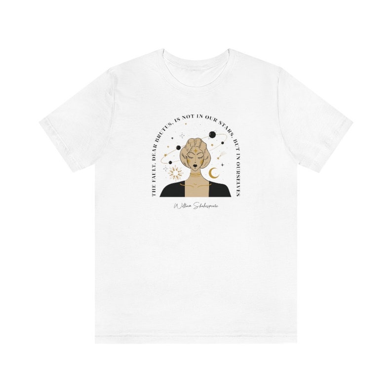 Może przedstawiać: Biały T-shirt z czarną i złotą ilustracją kobiety z gwiazdami i planetami wok&oacute;ł głowy. Tekst "The fault, dear Brutus, is not in our stars, but in ourselves" jest napisany w k&oacute;łku wok&oacute;ł kobiety. Tekst "William Shakespeare" jest napisany pod ilustracją.