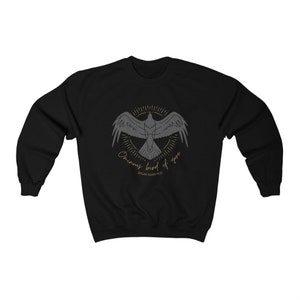 K&ouml;nnte beinhalten: Schwarzer Pullover mit einer grauen Silhouette eines Vogels mit dem Text "Ominous Bird of yore" und "Edgar Allan Poe" in goldener Schrift.