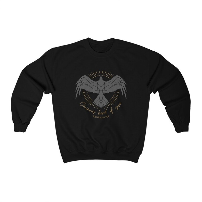 K&ouml;nnte beinhalten: Schwarzer Pullover mit einer grauen Silhouette eines Vogels mit dem Text "Ominous Bird of yore" und "Edgar Allan Poe" in goldener Schrift.