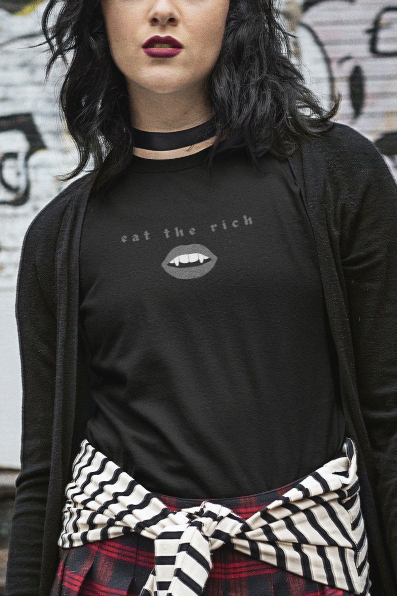 Puede incluir: Una camiseta negra de manga larga con un gr&aacute;fico blanco de una boca de vampiro con colmillos y el texto "eat the rich".